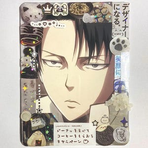 May include: A rectangular clear plastic frame decorated with various stickers including a central anime character portrait, food items like donuts and rice balls, a paw print, and Japanese text. The frame features holographic star accents.