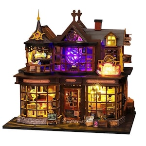 May include: A miniature two-story wooden model of a shop titled Magic Treasure House, featuring illuminated windows with warm yellow and purple LED lights, detailed storefront displays, a central entrance door, and a pointed roof structure.