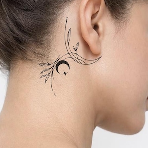 May include: A black, minimalist tattoo design featuring a crescent moon and star, with delicate floral and leaf accents. The tattoo is located on the nape of the neck, near the ear, and is composed of fine lines and dots.