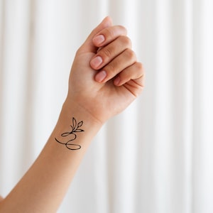 May include: A set of three ceramic mugs with a speckled, matte finish. Each mug features a different color: light blue, cream, and gray. The mugs have a simple, modern design with a rounded shape and a comfortable handle.