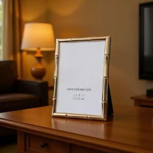 Könnte beinhalten: Ein goldfarbener Bilderrahmen mit Bambus-Design. Der Rahmen enthält einen weißen Einsatz mit dem Text "Regard every wonderful moment of your life" und den Abmessungen "4 x 6 in 101x152 mm". Der Rahmen steht auf einer Holzoberfläche.