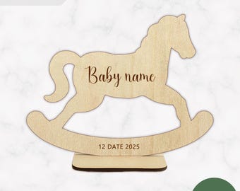 May include: A light-colored wooden rocking horse cutout on a rectangular base. The horse features the text Baby name in a script font on its body and the text 12 DATE 2025 on the curved rocker base. The design is a digital download file.