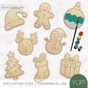 May include: Wooden Christmas-themed cutouts, including a Santa hat, gingerbread man, reindeer, snowman, Christmas tree, stocking, gift box, and ornament. Paint and a paintbrush are included. The text "DIGITAL DOWNLOAD" and "SVG CUTTING FILES | COMMERCIAL USE" are visible.