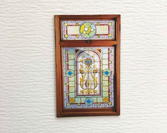 Puede incluir: Una ventana de vitrales con un diseño floral en tonos amarillos, azules y rojos. La ventana está enmarcada en madera.