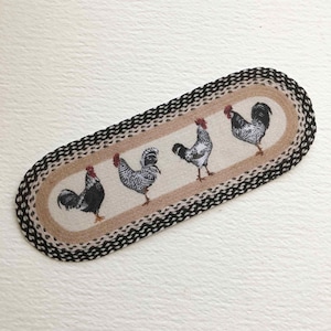 May include: A brown and black oval rug with a woven design and four black and white roosters printed on it.