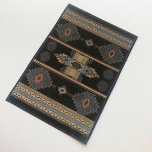 May include: A black and blue patterned rug with a geometric design. The rug has a woven texture and a fringed edge.