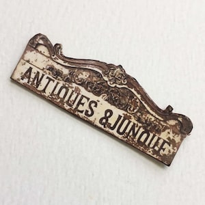 Letrero de papel envejecido y sucio con antigüedades en miniatura y chatarra