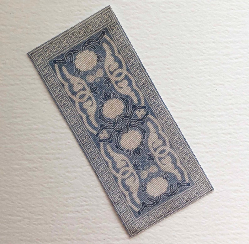 May include: A blue and white patterned rug with a geometric border. The rug has a repeating design of stylized flowers.