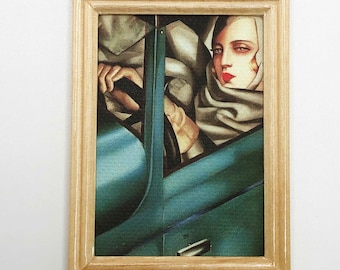May include: A framed painting of a woman in a car. The woman is wearing a white scarf and has red lips. The car is blue and green.