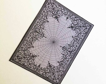 May include: A black and white patterned rug with a spiderweb design in the center. The rug has a gray background and a black border.