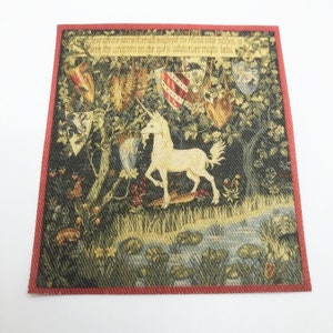 May include: A tapestry with a red border depicting a white unicorn standing in a forest with a stream and lily pads. The tapestry has text that reads "Where oft we are and sterially housed the round tower to give the unicorn on the quest si whatever might be found."