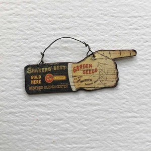 Miniatur-Weinlese-Werbung, die Hand mit Wörter-Schütteln-besten Garten-Samen verkauft hier zeigt