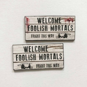 Letrero en miniatura a escala 'Bienvenidos mortales tontos asustados de esta manera' en el diseño que usted elija
