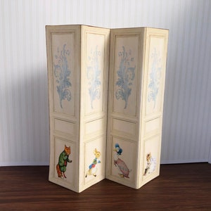 May include: A white folding screen with a blue floral design. The screen has four panels and features illustrations of a fox, rabbit, duck, and bunny.