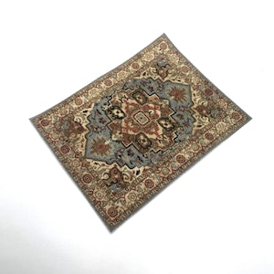 May include: A small, rectangular rug with an ornate, traditional design. The rug features a central medallion in shades of blue, red, and brown, surrounded by a beige border with floral patterns. The rug is likely made of woven fabric.