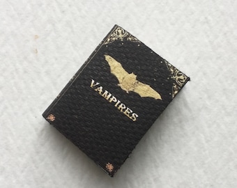 May include: A black book with a gold bat and the word "Vampires" on the cover.