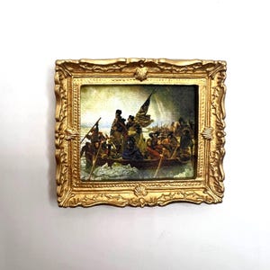 May include: A miniature framed print of a painting depicting a group of people in a boat on a stormy sea. The painting is in a gold frame with ornate details.