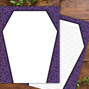 Może przedstawiać: Dwie kartki papieru listowego o tematyce Halloween. Fioletowa obw&oacute;dka ma wz&oacute;r dyni, nietoperzy i duch&oacute;w. Papier ma kształt trumny z białym wnętrzem i liniowaną przestrzenią do pisania. Papier leży na drewnianym tle.