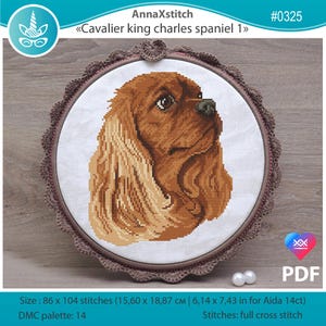 May include: A cross-stitch embroidery of a Cavalier King Charles Spaniel dog, displayed in a round frame with a decorative border. The artwork features shades of brown and tan, with the text "AnnaXstitch" and "Cavalier king charles spaniel 1". The size is 6.14 x 7.43 inches.