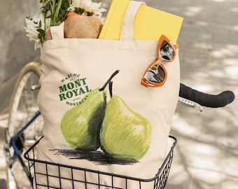 May include: A canvas tote bag with the text "MARCHE MONT ROYAL MONTREAL" and a green pear illustration. The bag is filled with a yellow book, flowers, and sunglasses. The bag is in a bicycle basket.