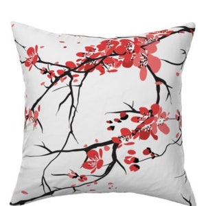 May include: White throw pillow with a black and red cherry blossom design.