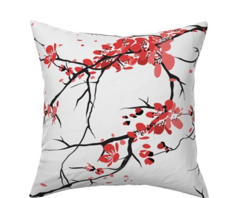 May include: White throw pillow with a black and red cherry blossom design.