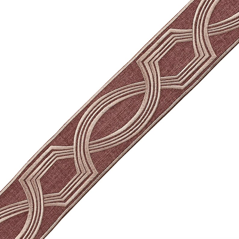 May include: A brown fabric trim with a geometric pattern in a lighter shade of brown. The pattern is made up of circles and octagons.