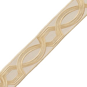 May include: Gold trim with a geometric pattern on a beige fabric. The trim has a repeating pattern of interlocking circles and squares.
