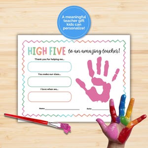 May include: A teacher gift certificate with the text "HIGH FIVE to an amazing teacher!" and fill-in sections. A pink handprint and a rainbow-painted hand are visible. A paintbrush with pink paint is on the bottom left. The text says "A meaningful teacher gift kids can personalize!"