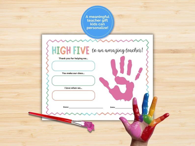 May include: A teacher gift certificate with the text "HIGH FIVE to an amazing teacher!" and fill-in sections. A pink handprint and a rainbow-painted hand are visible. A paintbrush with pink paint is on the bottom left. The text says "A meaningful teacher gift kids can personalize!"
