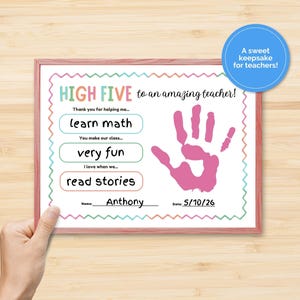 May include: A framed certificate with a pink handprint and the text "HIGH FIVE to an amazing teacher!" The certificate includes the phrases "learn math", "very fun", and "read stories". A blue circle says "A sweet keepsake for teachers!"