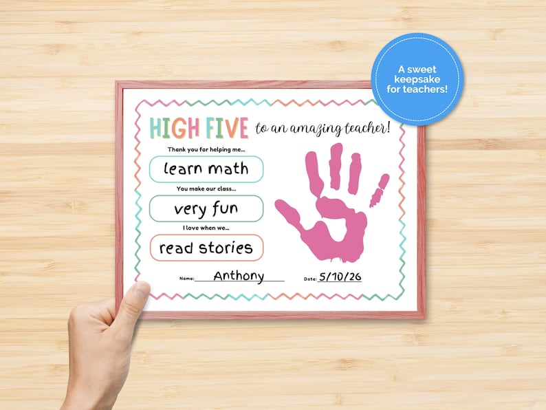 May include: A framed certificate with a pink handprint and the text "HIGH FIVE to an amazing teacher!" The certificate includes the phrases "learn math", "very fun", and "read stories". A blue circle says "A sweet keepsake for teachers!"