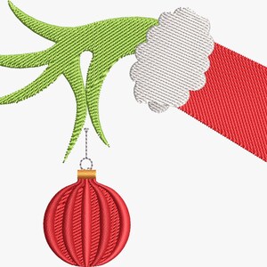 May include: An embroidered design featuring a green hand holding a red Christmas ornament. The hand has a white cuff and is set against a white background. The ornament is round with vertical lines.