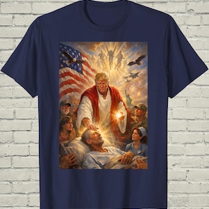 May include: Navy blue t-shirt featuring a religious-themed graphic. The artwork depicts a figure in a red robe with a glowing hand, surrounded by an American flag, eagles, and other figures. The design has a detailed, illustrative style.