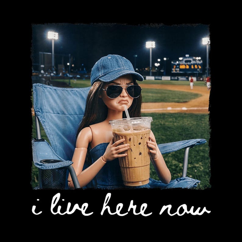 K&ouml;nnte beinhalten: Eine Puppe mit Jeansm&uuml;tze und Sonnenbrille, die in einem blauen Klappstuhl sitzt und einen gro&szlig;en Eiskaffee h&auml;lt. Die Puppe befindet sich nachts auf einem Baseballfeld. Der Text "i live here now" steht unten in wei&szlig;er Schrift.