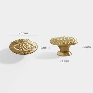 Puede incluir: Dos tiradores dorados para armarios. Uno es ovalado, de 46 mm de largo y 25 mm de ancho, con un dise&ntilde;o floral en relieve. El otro es un tirador redondo, de 30 mm de alto y 24 mm de ancho, con un patr&oacute;n en relieve similar. Herrajes decorativos.