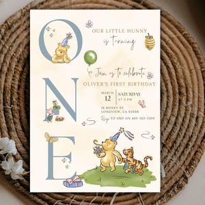 Pode incluir: Um convite de aniversário com o tema Ursinho Pooh. O convite apresenta o texto "Our Little Hunny is turning one" e "Join us to celebrate Oliver's First Birthday". O design inclui ilustrações de Pooh, Leitão e Tigrão.