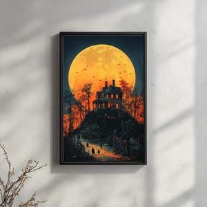 May include: A framed print depicts a spooky scene with a large orange moon dominating the night sky. A haunted house sits atop a hill, with a path leading towards it. Silhouettes of figures and trees add to the eerie atmosphere, with a black frame.