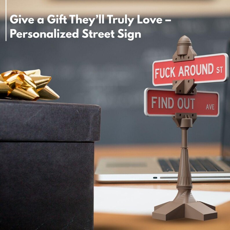 May include: A personalized street sign with the text "FUCK AROUND ST" and "FIND OUT AVE" in white on a red background. The sign is mounted on a brown decorative post. A black gift box with a gold bow is in the background.