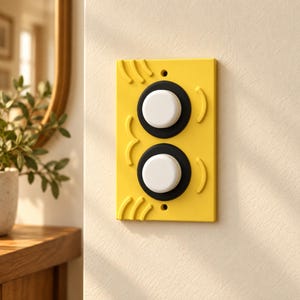 May include: A rectangular yellow light switch wall plate featuring two circular black accents surrounding white push-button switches. The yellow plate has a textured surface with raised curved lines along the left and right edges, and two screw holes for mounting.
