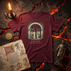 Può includere: T-shirt bordeaux con una grafica di due figure a un cancello con la scritta "ABANDON ALL HOPE YE WHO ENTER HERE" e "DANTE". Sono visibili anche una candela accesa, una moneta, un libro illustrato e una statua.
