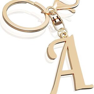 May include: Gold-colored keychain featuring the letter "A". The keychain includes a split ring, a lobster clasp, and a decorative letter pendant. The letter "A" is in a cursive font.