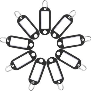 May include: A collection of ten black key tags arranged in a circular pattern. Each tag has a rectangular white label area and a small hole at the bottom. Silver key rings are attached to each tag.