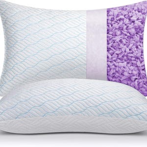 May include: Two white pillows with a wave pattern and blue stitching. One pillow is cut open to reveal a purple filling. The pillows are designed for comfort and support, perfect for a good night's sleep.