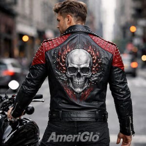 Può includere: Una giacca in pelle nera con pannelli rossi sulle spalle decorati con borchie argentate e una grande grafica di un teschio circondato da fiamme rosse sul retro. La giacca presenta un colletto, una cintura in vita e polsini con cerniera.