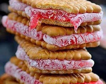 May include: A stack of ice cream sandwiches. Each sandwich features a rectangular, golden-brown biscuit and a layer of pink ice cream. The ice cream is partially melted and dripping down the sides, creating a tempting dessert.