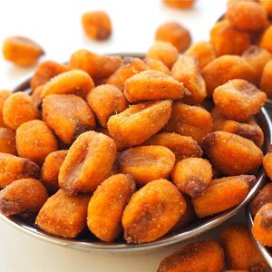 May include: Close-up of a silver bowl filled with golden-brown, roasted corn kernels. The kernels have a slightly rough texture and are coated in a light seasoning. A second bowl is partially visible in the background.