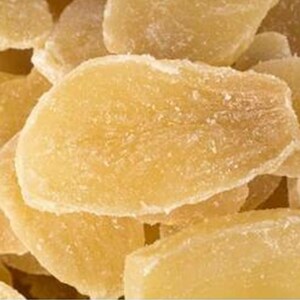 May include: Close-up of a pile of candied ginger slices. The ginger pieces are a light yellow color with a crystallized sugar coating. The texture appears slightly rough and uneven.