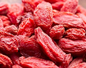 May include: A close-up shot of a heap of dried goji berries. The berries are a rich red hue and have a wrinkled appearance. They are clustered together, filling the frame. The image is well-lit, emphasising the colour and texture of the berries.