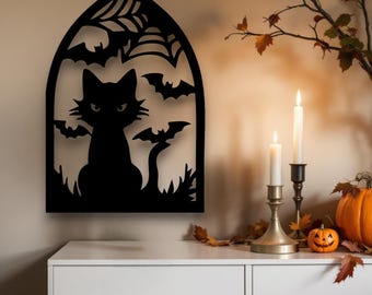May include: Black metal Halloween wall art depicting a cat, bats, and a spiderweb. The cat is within an arched frame. The artwork is displayed on a wall above a white table, with candles and pumpkins nearby.